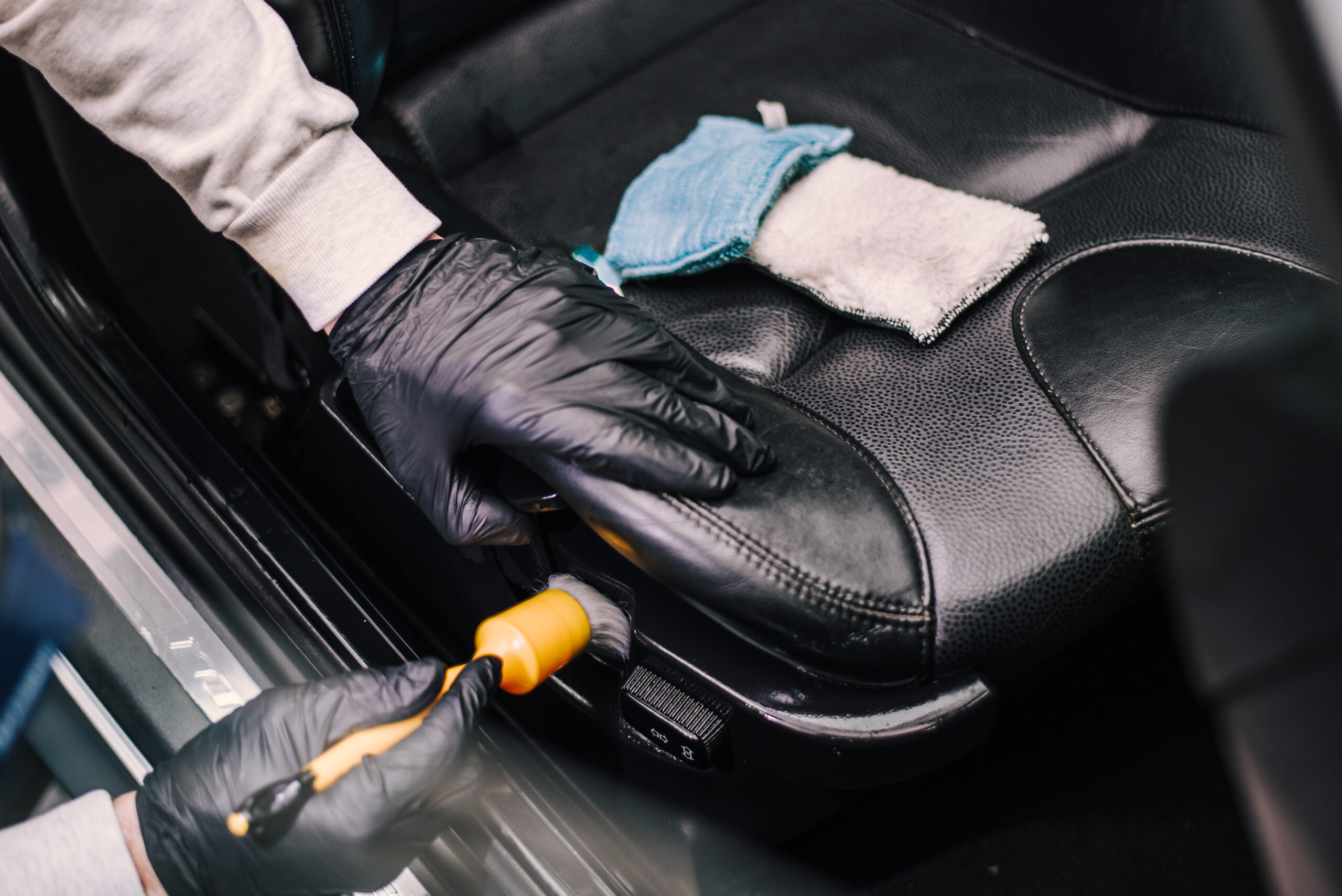 A man cleaning inside of black car with rubber brush